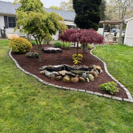 New Outdoor Space with Cobblestone Edge, fresh mulch and new brick Firepit